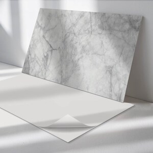 May include: A white marble contact paper with a peel-and-stick adhesive backing. The contact paper is shown with the adhesive backing peeled back.