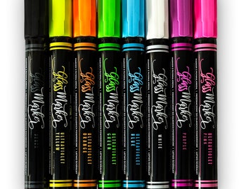 May include: A collection of eight glass markers in various colors, including black, yellow, orange, green, blue, white, purple, and pink. Each marker has a black barrel with the words "Glass Marker" and "Ultraviolet" printed on it.