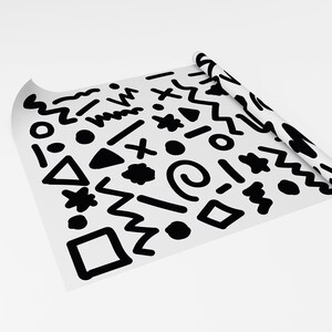 May include: A roll of white paper featuring a repeating pattern of black abstract shapes, such as zigzags, circles, and triangles. The paper is partially unrolled, displaying the design. The overall theme is modern and geometric.