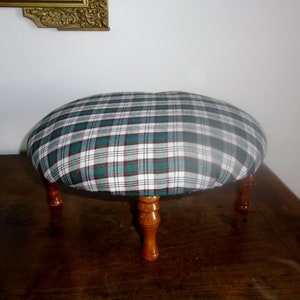 May include: A small, round, green and white plaid footstool with four wooden legs.