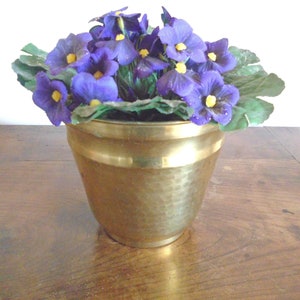 Peut inclure: Un pot en laiton martelé contenant un bouquet de fleurs violettes et jaunes.