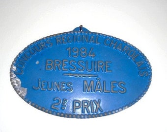 Puede incluir: Medalla ovalada de metal azul y plata con el texto "CONCOURS REGIONAL CHAROLAIS 1984 BRESSUIRE JEUNES MALES 2e PRIX"