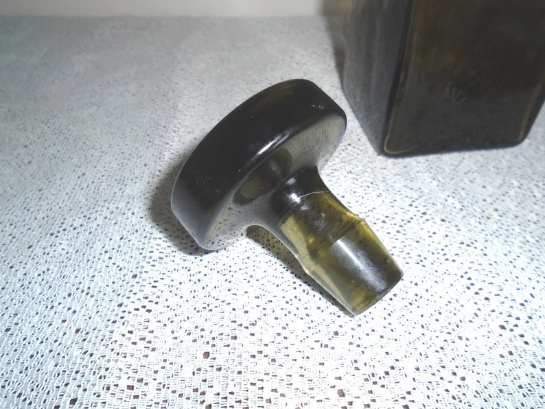 May include: A black glass bottle stopper with a round top and a clear glass neck. The stopper is designed to fit a bottle with a standard neck size.