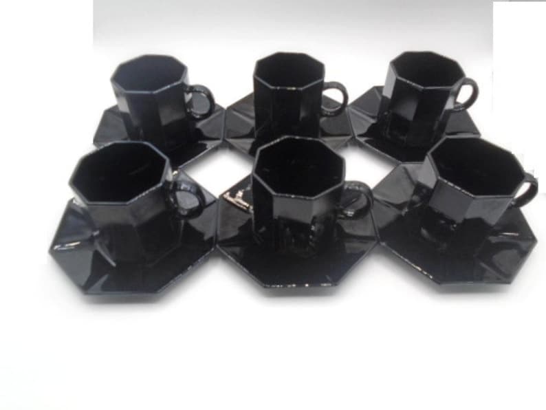 May include: Set of six black octagonal teacups and saucers. The cups and saucers are made of glass and have a glossy finish.