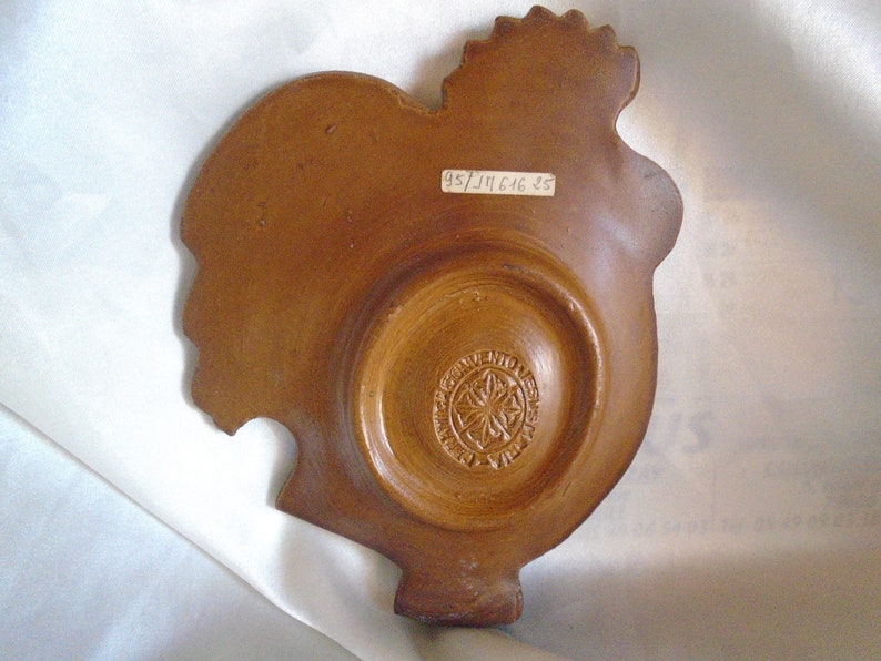 May include: A brown ceramic rooster dish with a decorative design on the bottom. The dish has a label on the back that reads "95/311646 35".