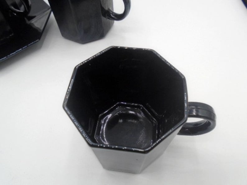May include: A black octagonal ceramic coffee mug with a handle. The mug is empty and the inside is visible.