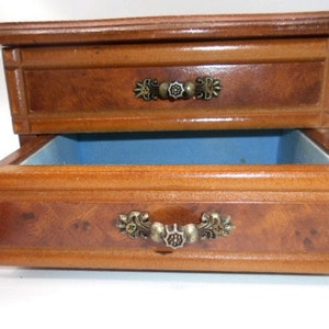 Peut inclure: Une bo&icirc;te &agrave; bijoux en bois avec deux tiroirs. Le tiroir sup&eacute;rieur a une poign&eacute;e en m&eacute;tal d&eacute;corative. Le tiroir inf&eacute;rieur est doubl&eacute; de feutre bleu.