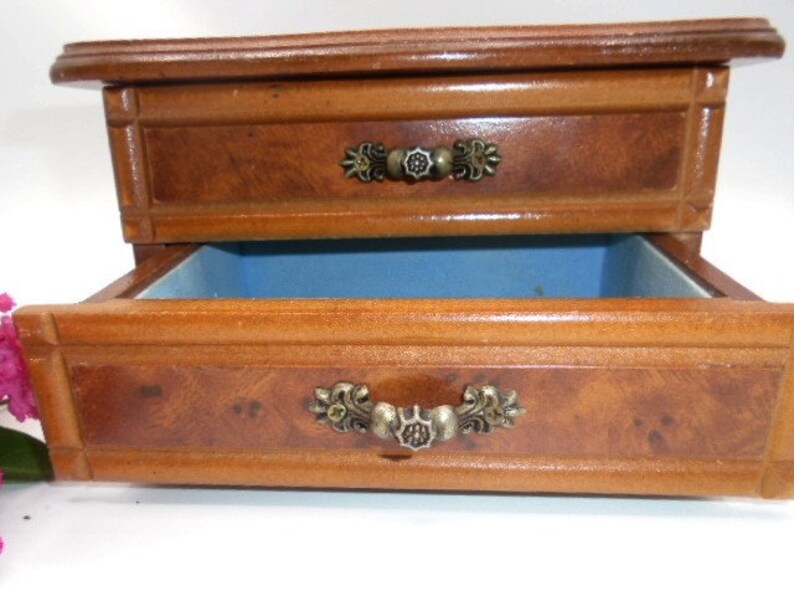 Peut inclure: Une bo&icirc;te &agrave; bijoux en bois avec deux tiroirs. Le tiroir sup&eacute;rieur a une poign&eacute;e en m&eacute;tal d&eacute;corative. Le tiroir inf&eacute;rieur est doubl&eacute; de feutre bleu.