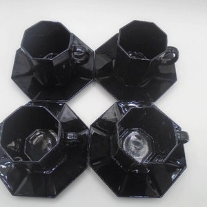 May include: Set of four black octagonal ceramic teacups and saucers. The cups and saucers have a glossy finish.