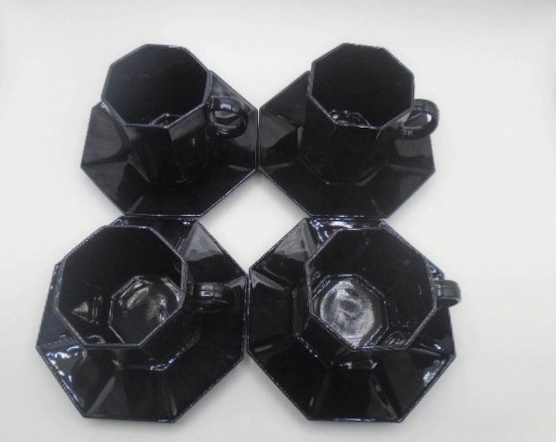 May include: Set of four black octagonal ceramic teacups and saucers. The cups and saucers have a glossy finish.