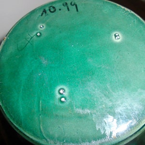 Peut inclure: Le fond d'un vase en c&eacute;ramique vert avec la date "10.19" inscrite dessus.
