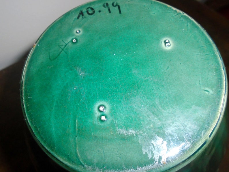 Peut inclure: Le fond d'un vase en c&eacute;ramique vert avec la date "10.19" inscrite dessus.