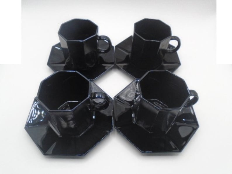 May include: Set of four black octagonal ceramic teacups and saucers. The cups and saucers have a glossy finish.