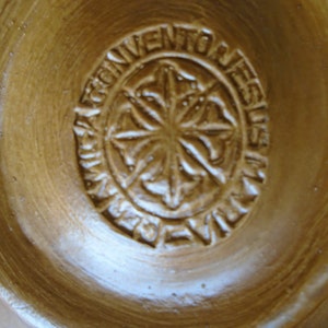 May include: Close-up of a brown clay bowl with a circular stamp that reads "Convento de Jesus".