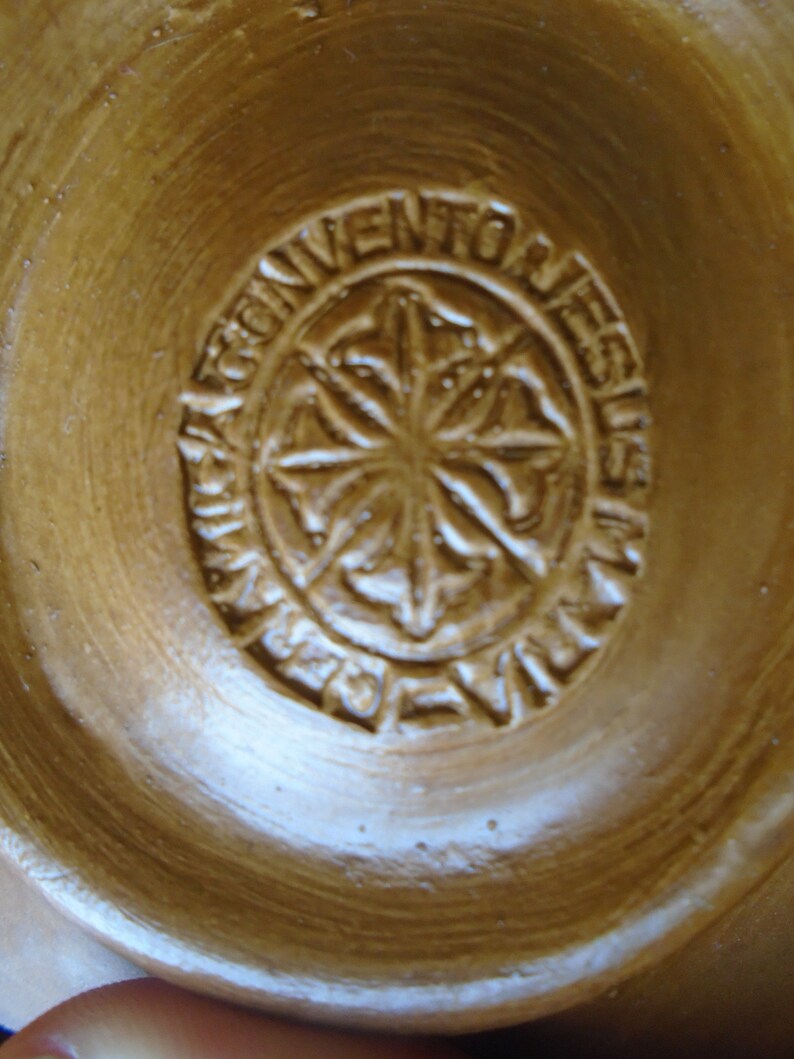 May include: Close-up of a brown clay bowl with a circular stamp that reads "Convento de Jesus".