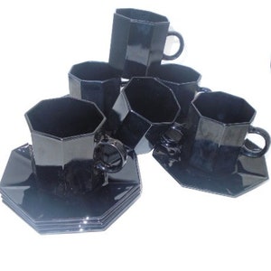 May include: Set of six black octagonal teacups and saucers. The cups and saucers are made of glass and have a glossy finish.