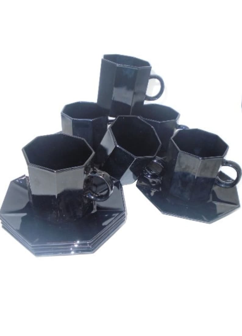 May include: Set of six black octagonal teacups and saucers. The cups and saucers are made of glass and have a glossy finish.