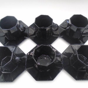 May include: Set of six black octagonal ceramic teacups and saucers. Each cup and saucer has a geometric design.