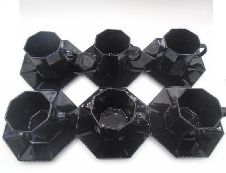 May include: Set of six black octagonal ceramic teacups and saucers. Each cup and saucer has a geometric design.