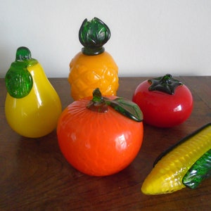 May include: A set of five glass fruit sculptures, including a pineapple, pear, orange, tomato, and corn. The sculptures are all brightly colored and have realistic details.