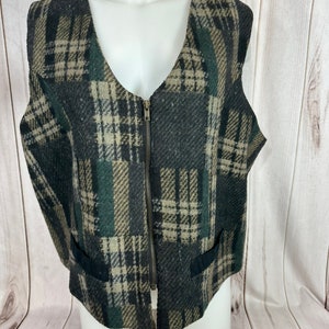 May include: A black, green, and brown plaid vest with a zipper closure. The vest has two pockets on the bottom.