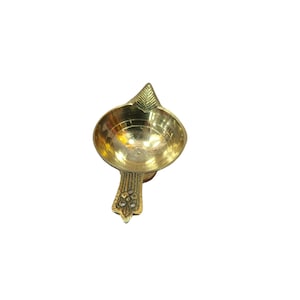May include: A small, gold-colored brass diya, a traditional Indian oil lamp, with a decorative handle.