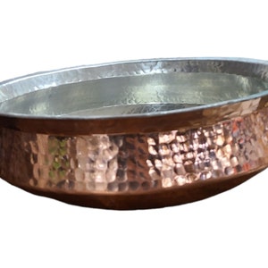 Könnte beinhalten: Eine gehämmerte Kupferschale mit silbernem Innenraum. Die Schale hat eine abgerundete Form und einen leicht ausgestellten Rand.