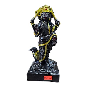 May include: Black statue of a Hindu deity with a golden crown and jewelry, holding a weapon in each hand. The deity is standing on a black base with a bird at its feet. The price tag reads "$25.00".