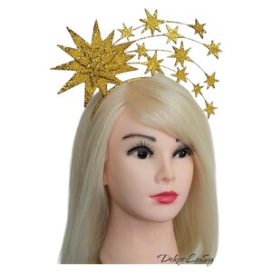 May include: Gold glitter starburst headband with a row of smaller gold glitter stars. The headband is a festive accessory for a party or special occasion.