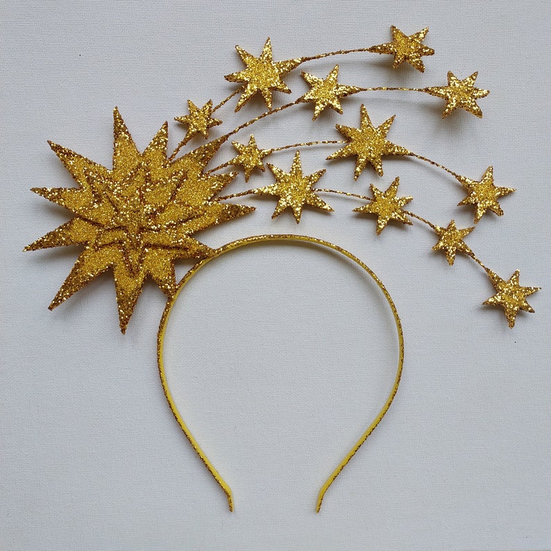May include: Gold headband with a large starburst design and smaller stars cascading down the sides. The headband is perfect for a festive occasion.