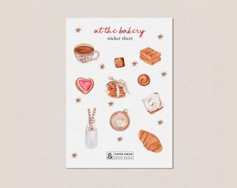 May include: A sticker sheet with the text "at the bakery" and a variety of bakery-themed illustrations, including a cup of coffee, a croissant, a cinnamon roll, a heart-shaped cookie, a stack of cookies, a waffle, and a bottle of milk with straws. The illustrations are in watercolor style and have a warm, inviting aesthetic.