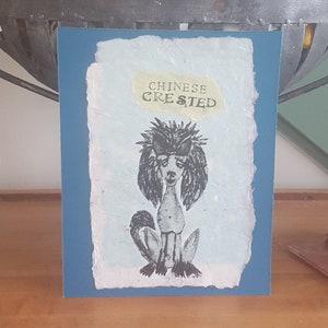 May include: A blue card with a white background and a black and white illustration of a Chinese Crested dog. The text "CHINESE CRESTED" is printed in yellow on the card.