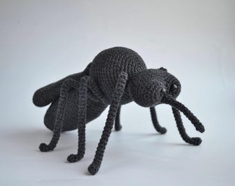 May include: A crocheted black ant plush toy with large eyes and long legs.