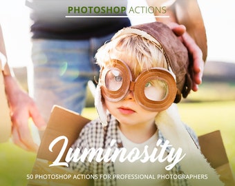 May include: A young child wearing brown aviator goggles and a brown leather hat is looking at the camera. The child is holding a cardboard box and is standing in a field. The text "Luminosity" is written in a white cursive font on the image. The text "50 Photoshop Actions for Professional Photographers" is written in black text below the word "Luminosity".