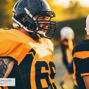 May include: Two football players wearing orange and black uniforms with helmets. The player in the foreground is looking to the right and has a tattoo on his arm.