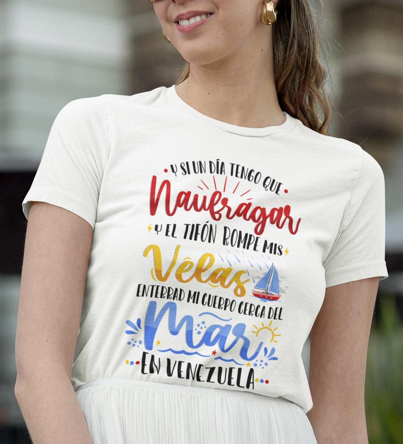 May include: White t-shirt with a colourful graphic design that says "Y si un dia tengo que Naufragar y el tif&oacute;n rompe mis Velas Enterrad mi cuerpo cerca del Mar en Venezuela."