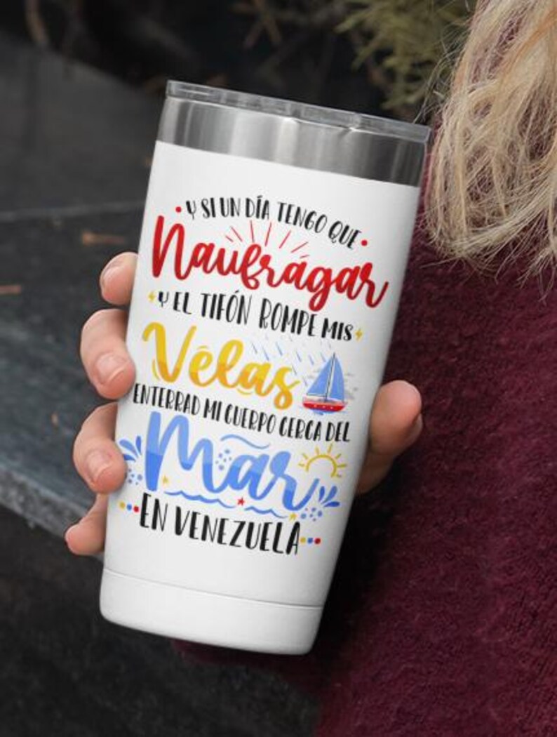 May include: White stainless steel tumbler with a colourful graphic design featuring a sailboat and the text "Y SI UN DIA TENGO QUE. Naufragar Y EL TIFON ROMPE MIS Velas ENTERRAD MI CUERPO CERCA DEL Mar EN VENEZUELA."