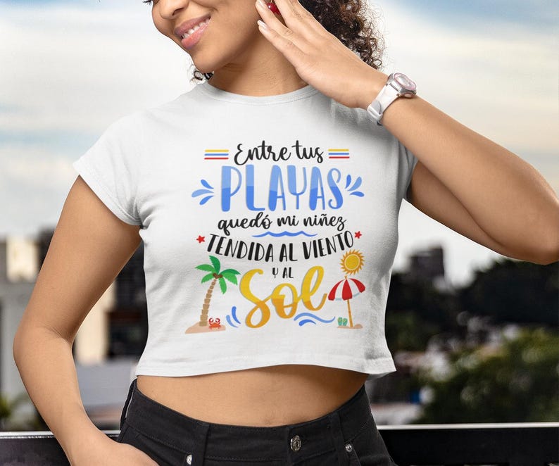 May include: White crop top with the text "Entre tus playas qued&oacute; mi ni&ntilde;ez tendida al viento y al sol" with a palm tree and an umbrella graphic.