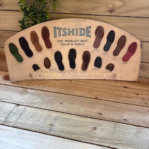 May include: Vintage ITSHIDE display featuring various shoe sole and heel designs in brown, black, and green. The sign reads "THE WORLD'S BEST SOLES & HEELS" and includes text such as "GOLFER" and "COMMANDO".