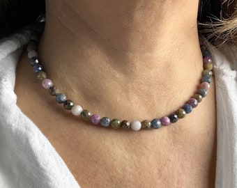 Könnte beinhalten: Eine mehrfarbige Edelstein-Halskette mit einer Auswahl an blauen, grünen, rosa und braunen Perlen. Die Halskette besteht aus facettierten Perlen und ist auf einer durchsichtigen Schnur aufgefädelt.