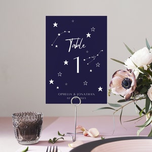 May include: Navy blue table number card with white stars and constellations. The card says "Table 1" and "Ophelia & Jonathan 07 08 2023".