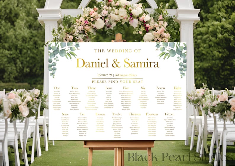 May include: A wedding seating chart with a white background and gold lettering. The chart is decorated with green eucalyptus leaves and has the names "Daniel & Samira" at the top. The chart lists tables numbered one through fifteen.