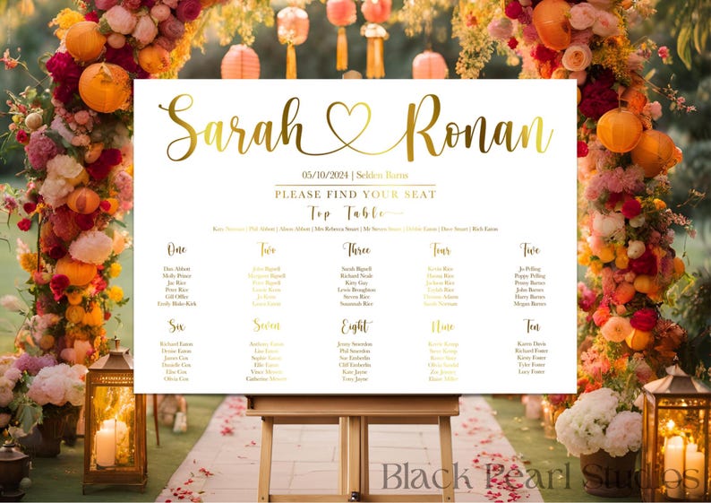 May include: A white wedding seating chart with gold lettering, displaying the names "Sarah & Ronan" and the date. The chart is on an easel, surrounded by floral arrangements and lanterns.