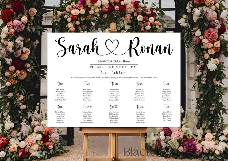 May include: A wedding seating chart with the names "Sarah" and "Ronan" in elegant script, separated by a heart symbol. The date "05/10/2024" is displayed, along with the venue. The chart is on a wooden easel, surrounded by floral arrangements.