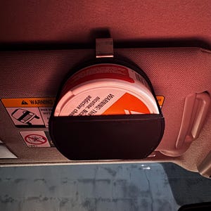 Peut inclure: Une pochette en cuir noir avec un clip en m&eacute;tal, con&ccedil;ue pour contenir un r&eacute;cipient rond. Le r&eacute;cipient est blanc et orange, avec l'avertissement "WARNING: This product contains nicotine. Nicotine is an addictive chemical."