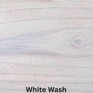 May include: Close-up of a white-washed wood surface. The wood grain is visible, with horizontal lines and a knot. The text "White Wash" is displayed in a black, bold font at the bottom of the image.