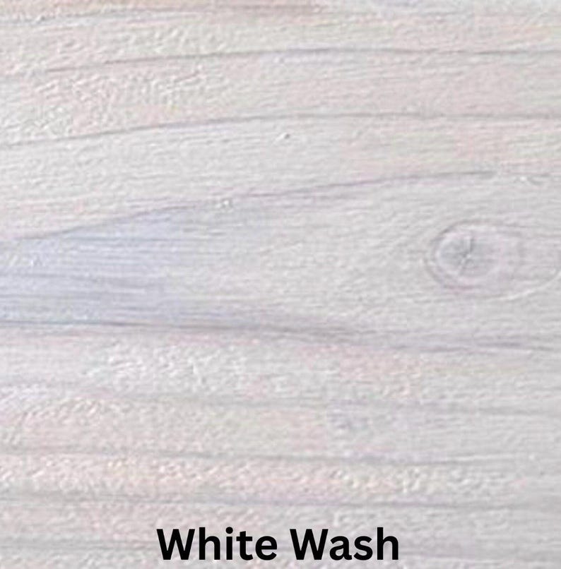 May include: Close-up of a white-washed wood surface. The wood grain is visible, with horizontal lines and a knot. The text "White Wash" is displayed in a black, bold font at the bottom of the image.