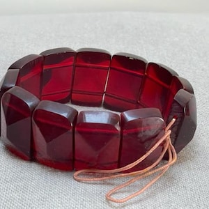 Pulsera rígida vintage de celuloide, color rojo cereza, con rosca y diseño art déco. Ancho ajustable.