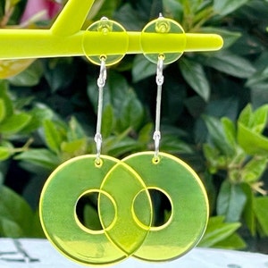May include: A pair of yellow, translucent, circular earrings with a smaller circle cut out of the center. The earrings are suspended from silver hooks.