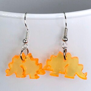 May include: A pair of yellow dinosaur shaped earrings with silver hooks.